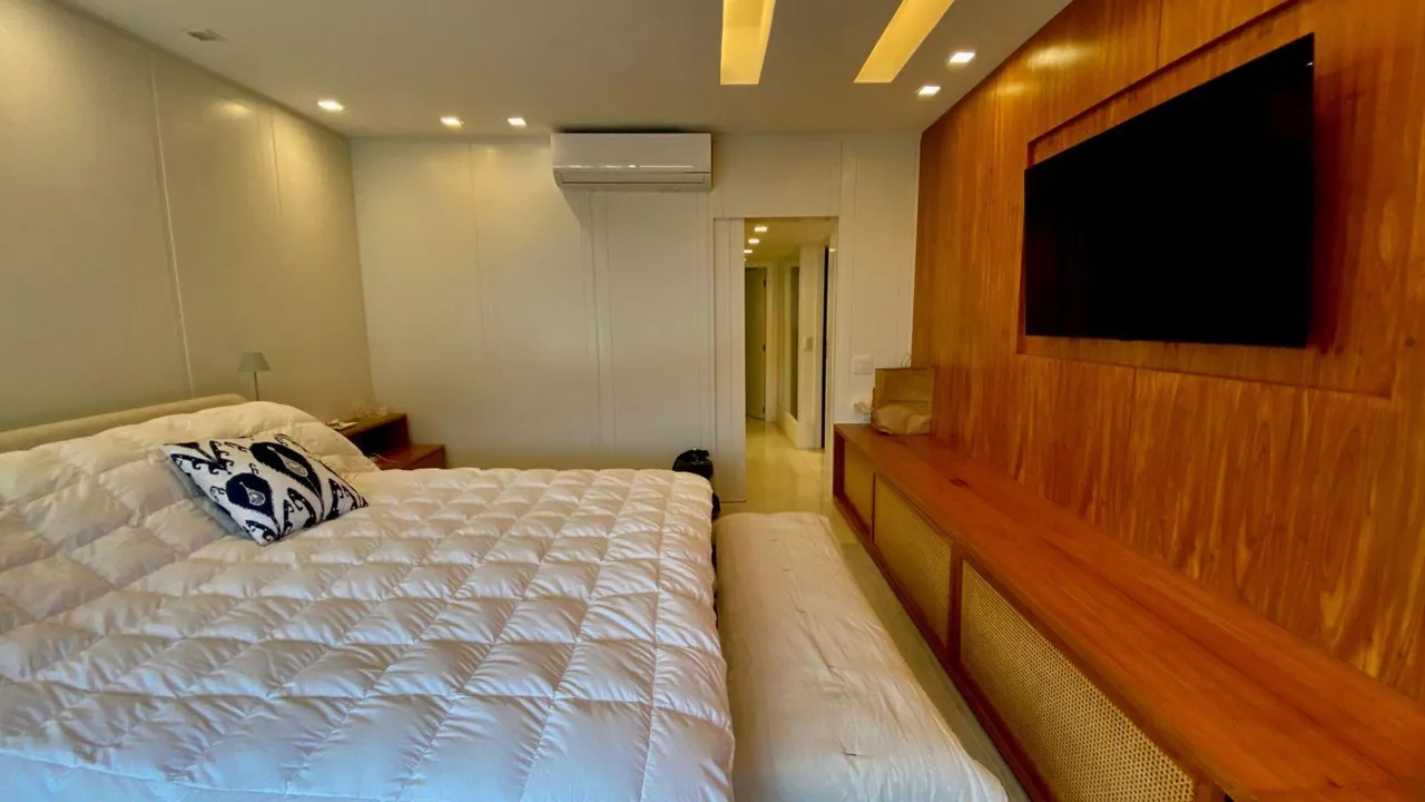 Suíte principal com cama de casal e painel de madeira