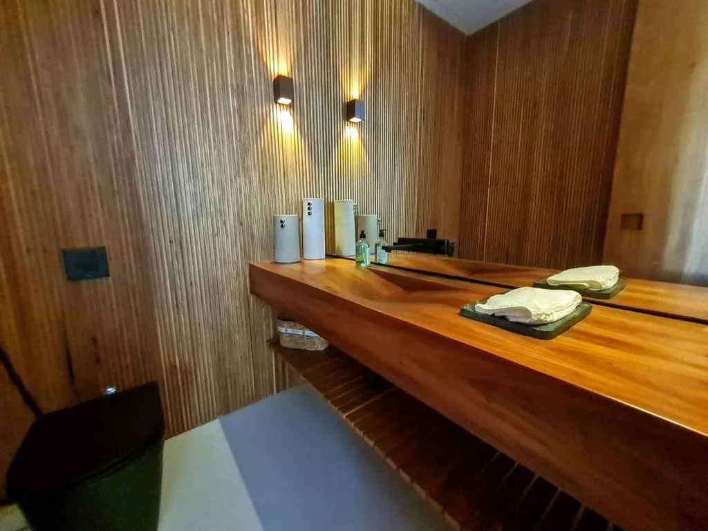 Banheiro com bancada em madeira e toalhas dobradas