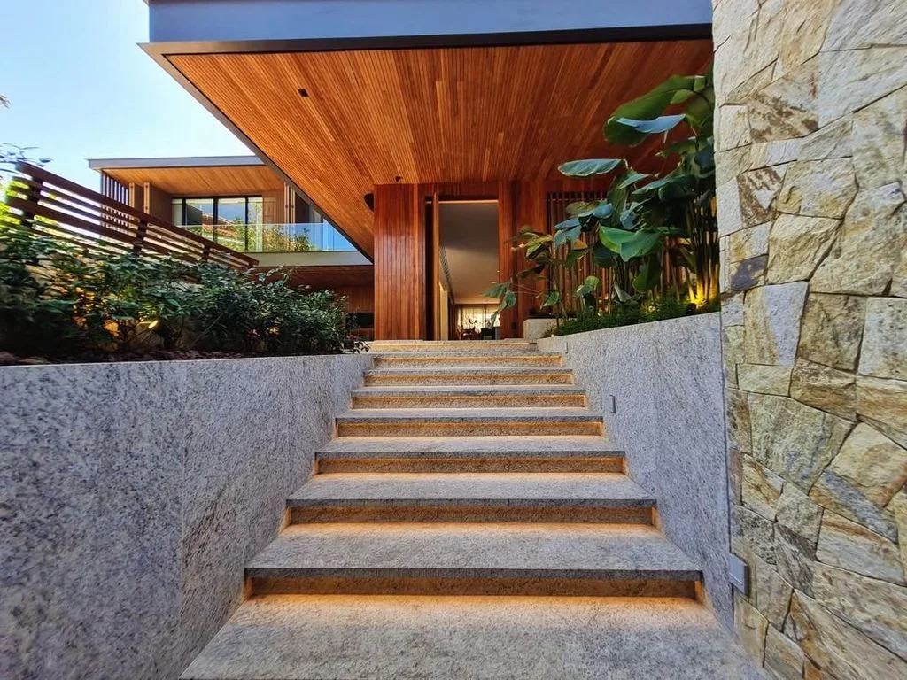 Escada de pedra na entrada da casa, cercada de vegetação