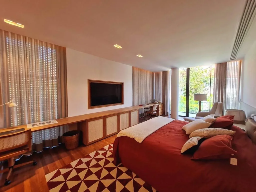 Quarto com cabeceira estofada em vermelho e tapete geométrico