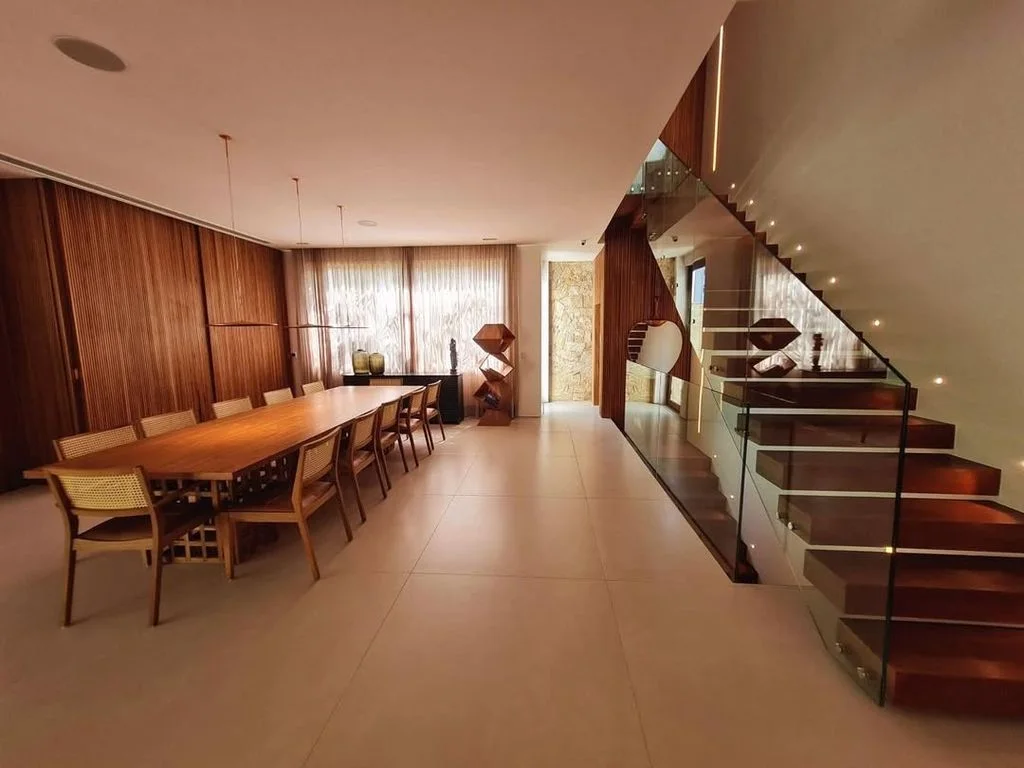 Sala de jantar integrada com escada de vidro ao fundo