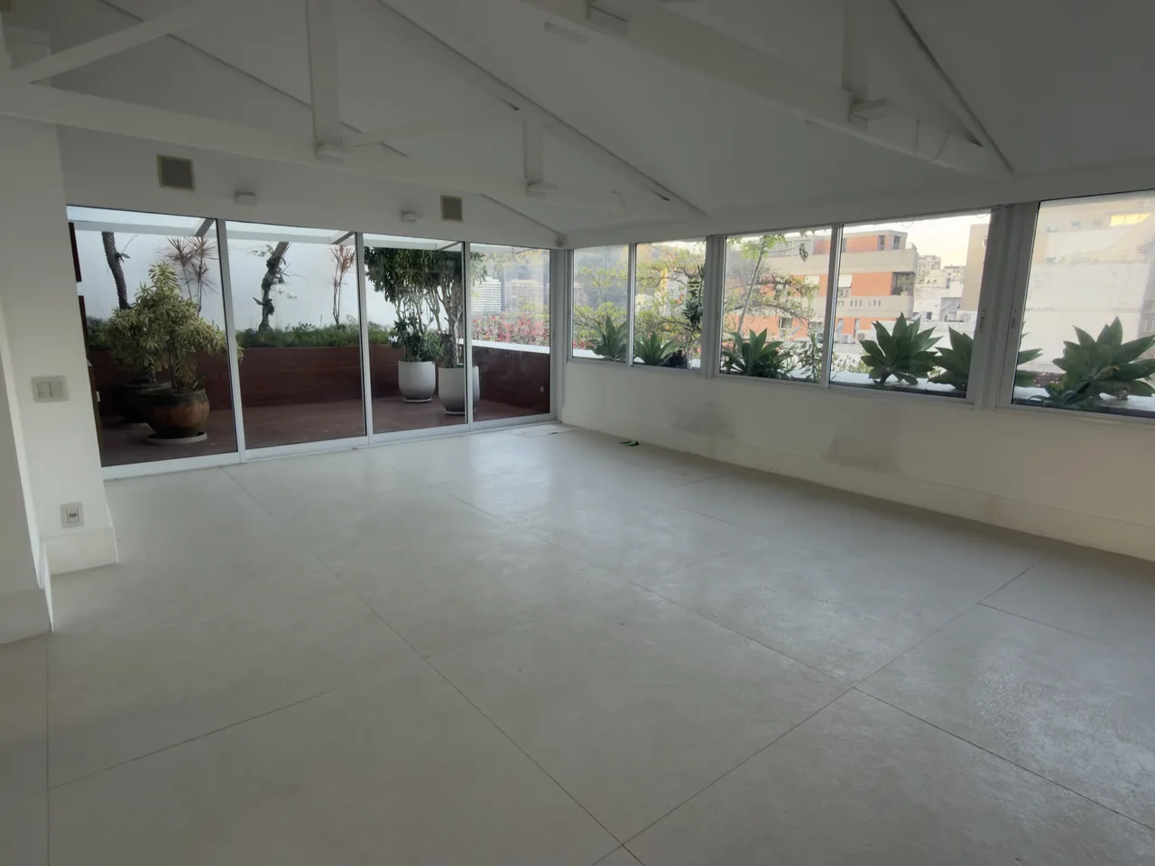Sala integrada com pé-direito alto e vista para o terraço