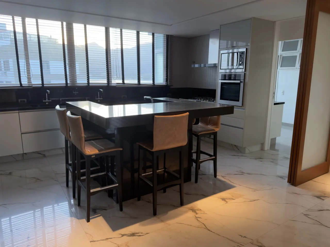 Cozinha com ilha em mármore e banquetas