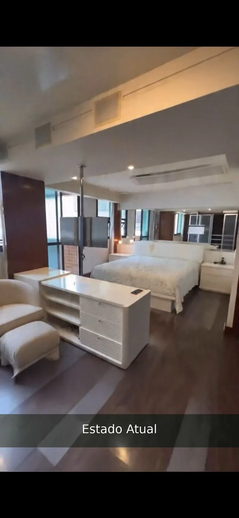 Estado atual: quarto amplo com piso de madeira escura e armários brancos