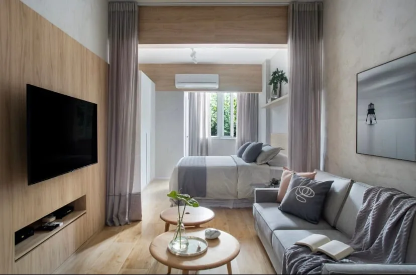 Sala e quarto integrados do loft, com TV e janela ao fundo