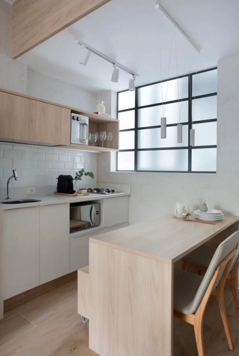 Cozinha com cooktop, micro-ondas e bancada com cadeira