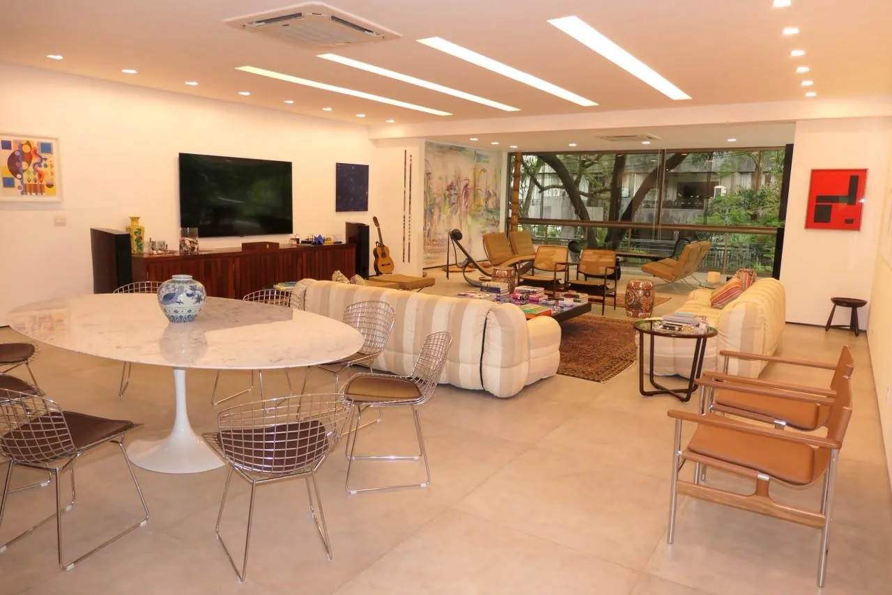 Living integrado com sala de jantar em mármore e TV, sofá listrado ao fundo