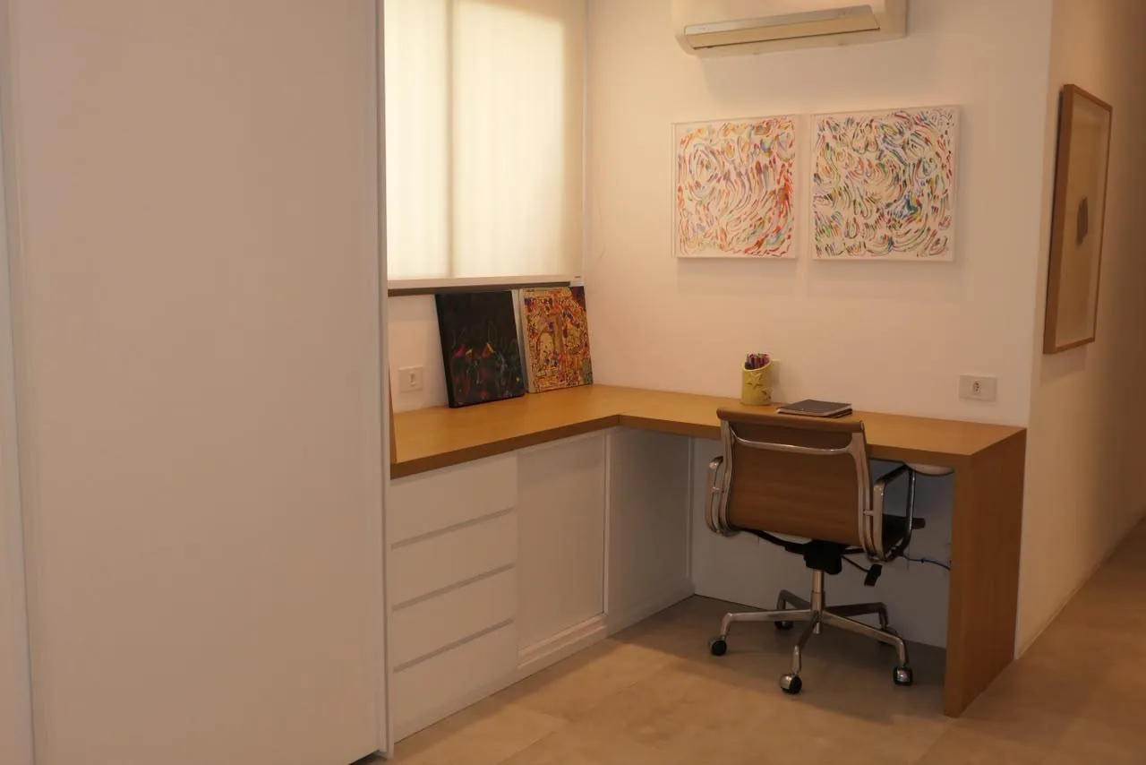 Escritório com bancada de madeira e obras de arte