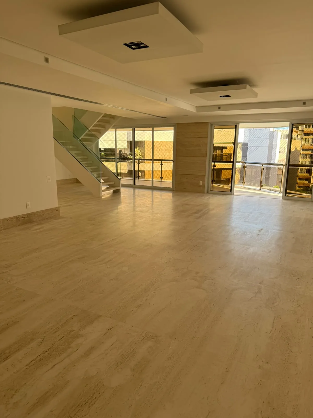 Sala com escada de vidro e vista para a montanha