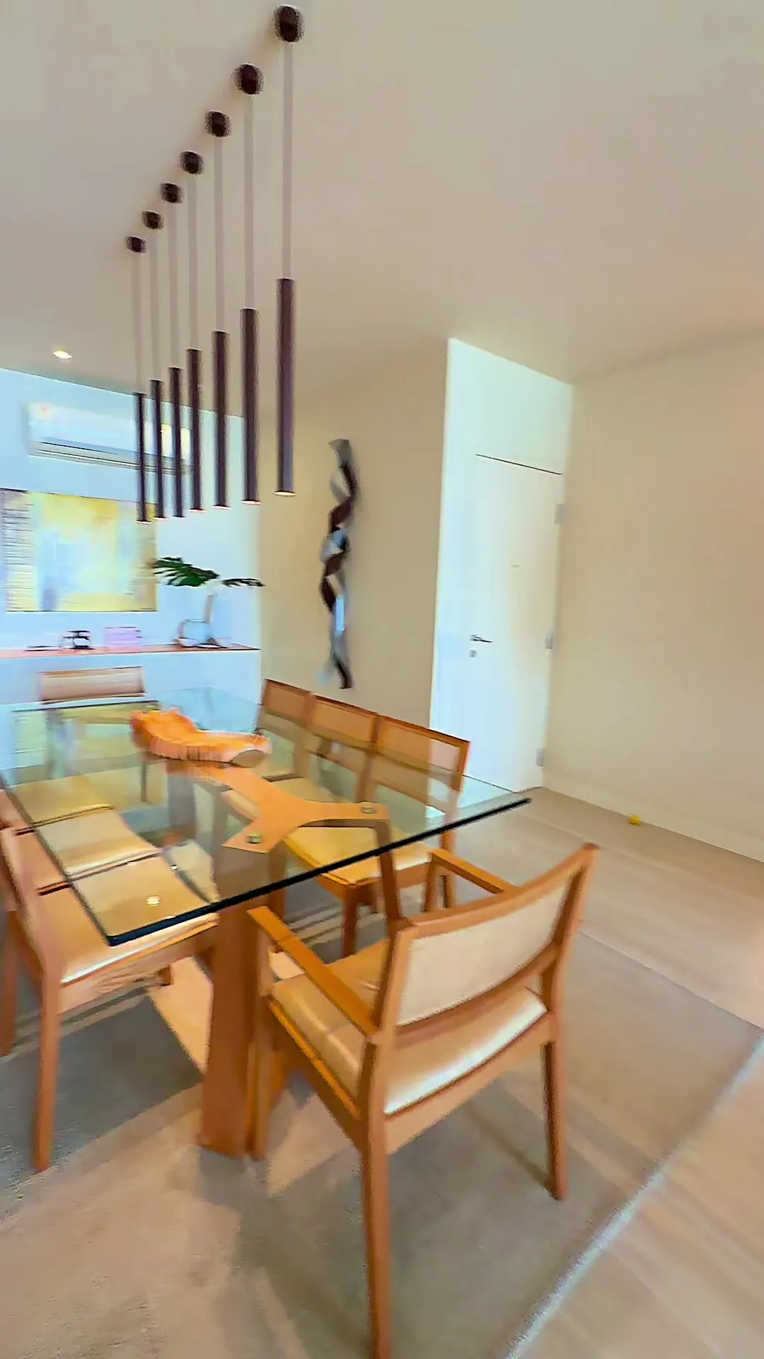 Sala de jantar com mesa de vidro e luminárias pendentes