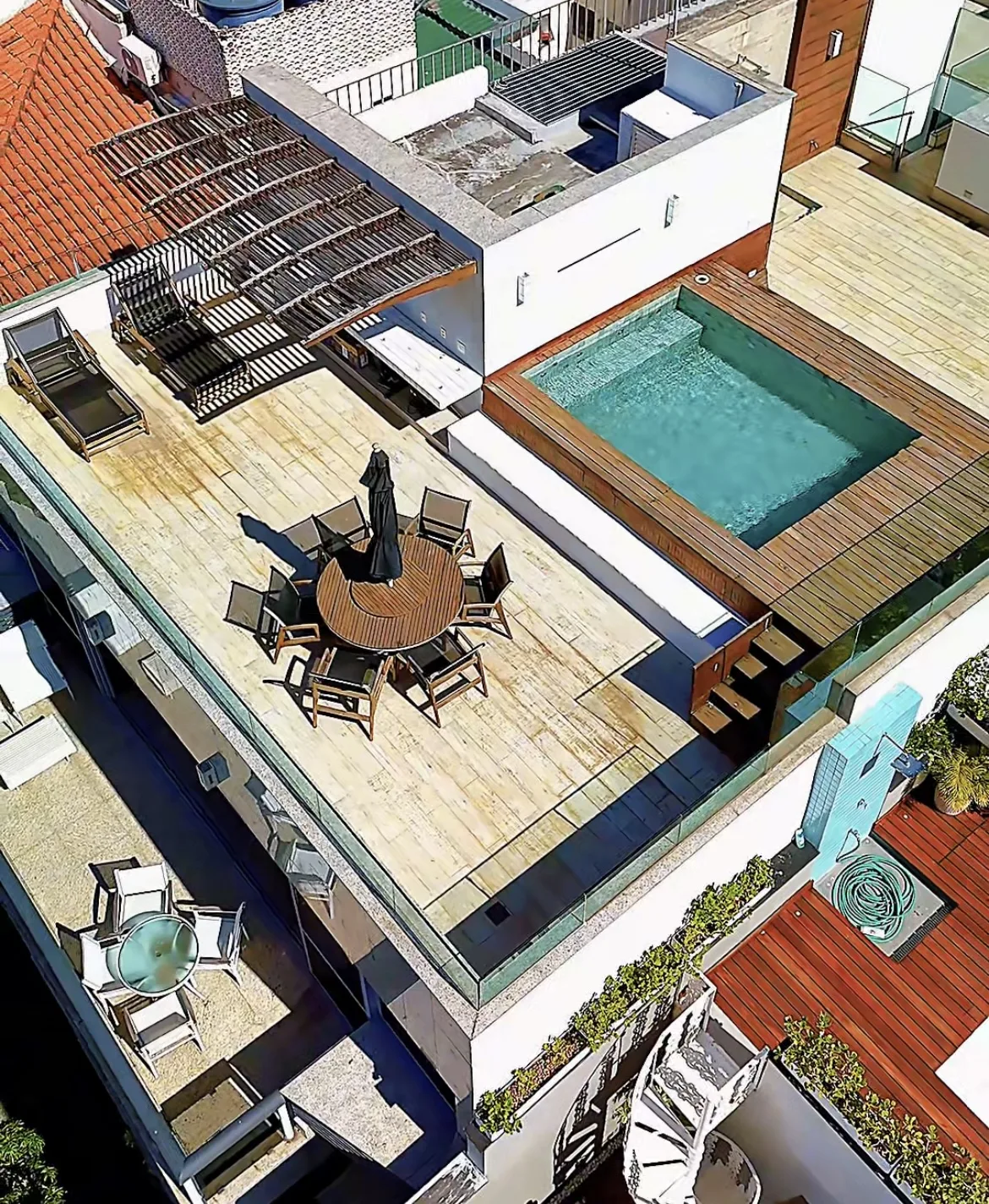 Vista aérea do terraço com piscina, estar externo e pergolado de madeira