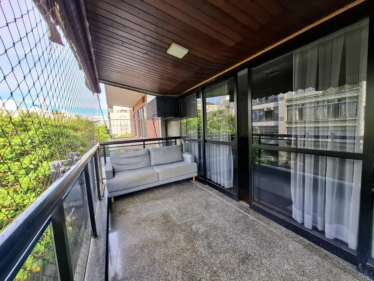 Varanda com sofá e vista para o verde