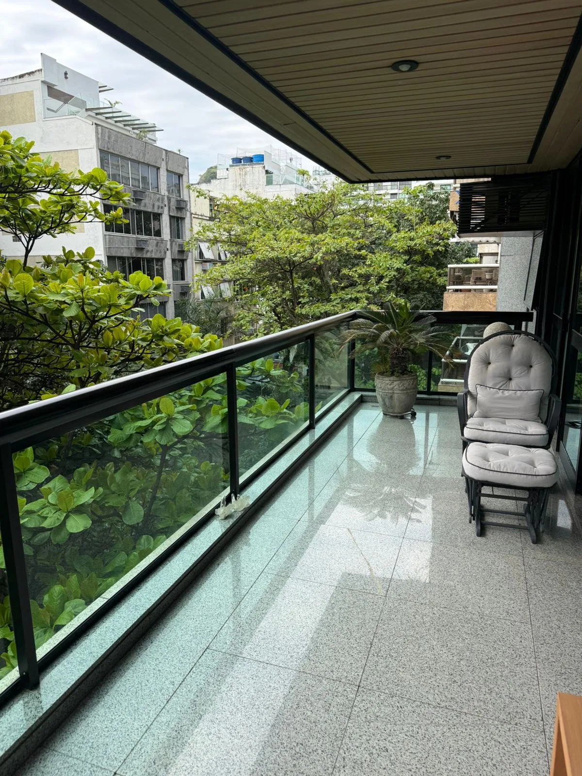 Varanda com poltrona e vista para o arvoredo da rua