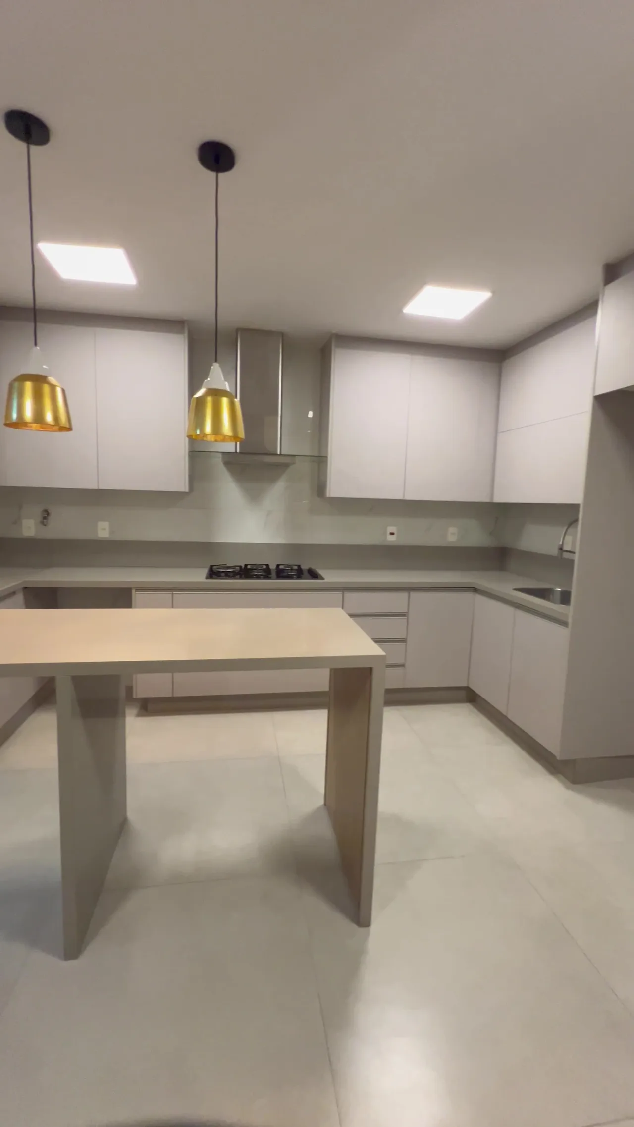 Cozinha moderna com ilha central e pendentes dourados