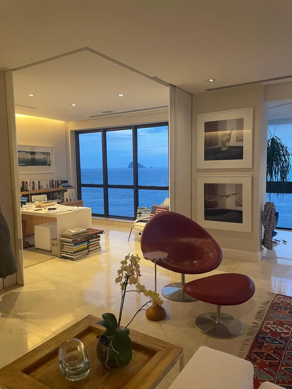 Ambiente com poltronas, escritório e janelas para o mar