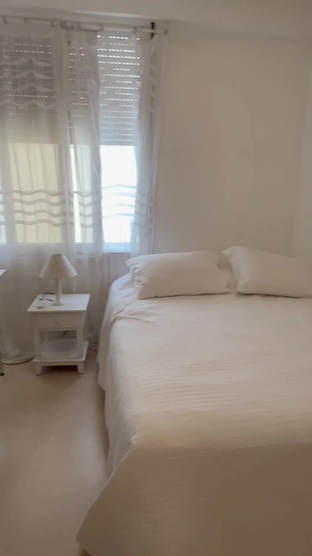 Suíte com cama de casal e cortinas claras